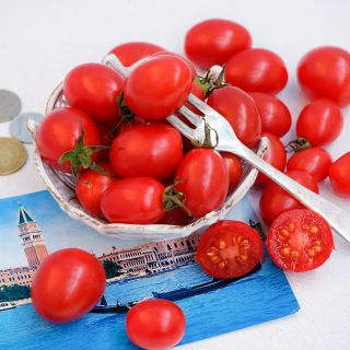 A Grappoli D'Inverno Tomatoes in a bowl with a postcard from Italy and some Italian coins.
