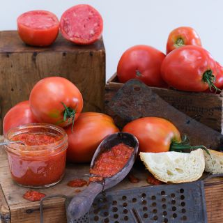 Amish Paste Tomatoes processed as paste in a jar and spoon arrange on on wooden boxes.