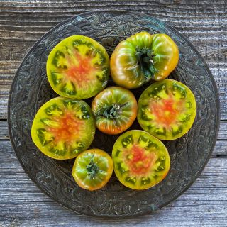 Cut and whole Ananas Noire or Black Pineapple Tomatoes on a platter. Image by Lucy Hutchins.