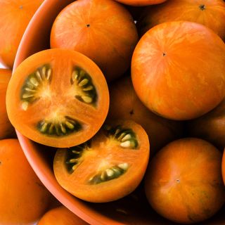 Close-up detail of whole and cut Apricot Zebra Tomatoes.