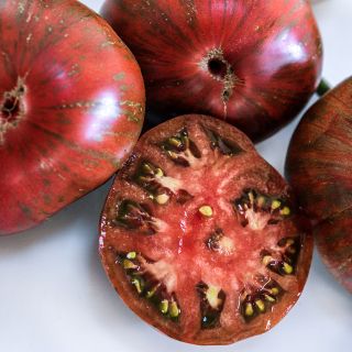 Cut and whole Berkeley Pink Tie-Dye Tomatoes on a white background.