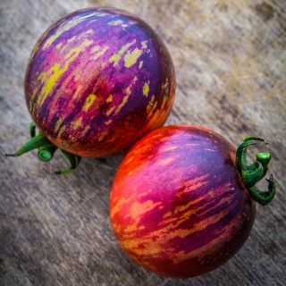Close-up of a couple of Black Strawberry Tomatoes on a wood background.