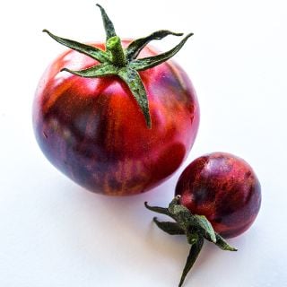 A pair of ripe Black Strawberry Tomatoes on white background.