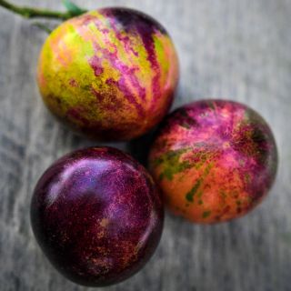 A close-up of a Trio of Black Strawberry Tomatoes on a wooden background.