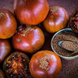 Whole Brown Sugar Tomatoes with slices and brown sugar in a bowl.
