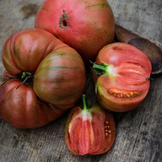 Cut and whole Dester Tomatoes with an old wooden spoon on wood background.