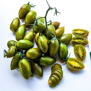A cluster of whole and cut Lucky Tiger Tomatoes on white background.