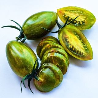 Close-up macro view of whole and sliced Lucky Tiger tomatoes n a white background.