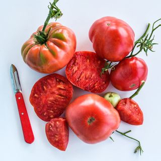 Cut and whole Missouri Pink Love Apple Tomatoes arranged on white background.