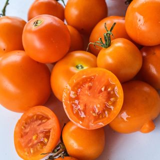 Close-up of cut and whole Auriga Tomatoes on a white background.
