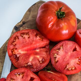 Close-up of cut and whole Wood's Famous Brimmer Tomatoes on wood cutting board.