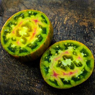 Cut Berkeley Tie-Dye Green Tomato on wooden cutting board.