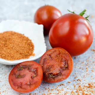A close-up of cut and whole Brown Sugar Tomatoes with brown sugar in dish.