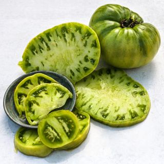 Sliced and whole Green Giant Tomatoes on white background.