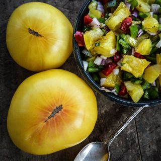 Colorful salsa in a bowl made out of Hugh's Tomatoes with a couple of whole tmatoes on the side