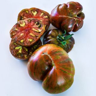 Sliced and whole Large Barred Boar Tomatoes on a bright white background.