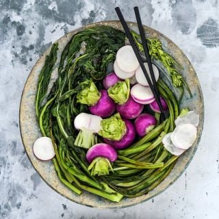 Nagasaki Akari Kabu Turnips with sauteed greens plated in a ceramic bowl on a light background.