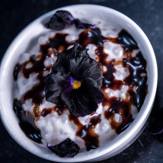 Black Devil Pansy flower floating in bowl on a dark background.
