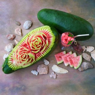 Art Combe's Ancient Watermelon with carved flowers and cut melon on a pastel background.