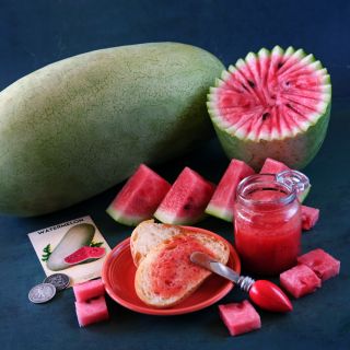 Whole and sliced Charleston Gray Watermelon with watermelon jam on dark blue background.