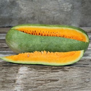 Texas Golden Watermelon with a slice cut out of it on wooden background.