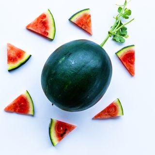 Black Jewel Watermelon with wedges on light background.