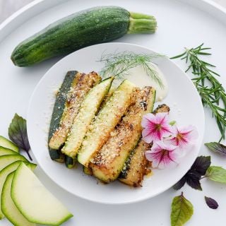 Breaded air fried Black Beauty Zucchini Summer Squash on a plate with garnish.