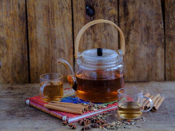 Teapot and cups on book against wood background