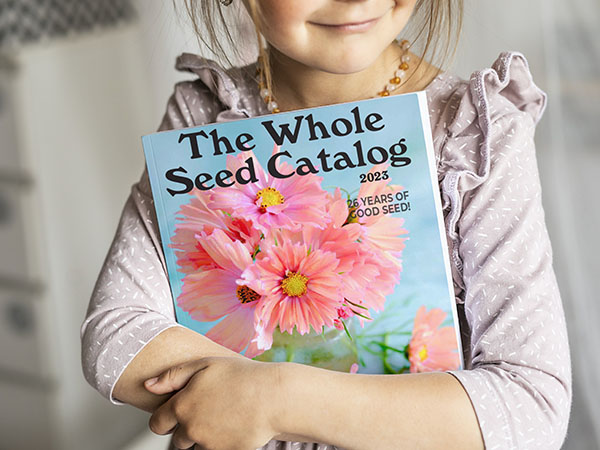 Girl holding 2023 Whole Seed Catalog